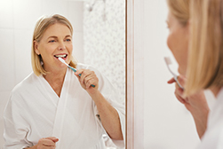 Woman brushing teeth before oral hygiene checkup at Cooley Smiles 