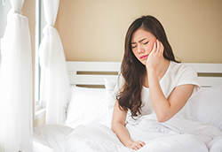 Woman with hurting jaw needs to see dentist at Cooley Smiles 