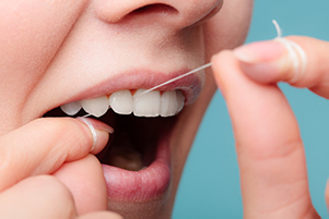 A woman flossing her teeth at Cooley Smiles in Everett, WA