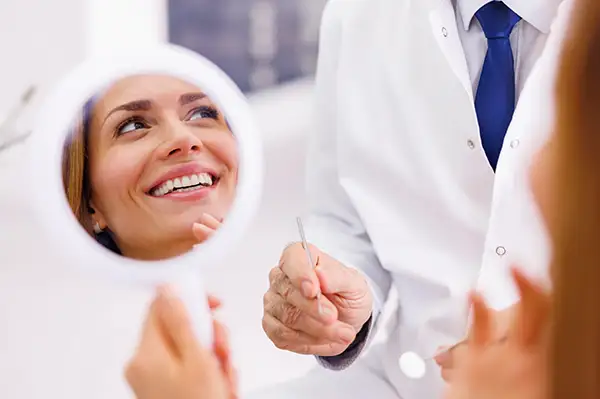 Woman smiling with beautiful teeth after gum disease treatment and looking at her dentist at Cooley Smiles in Everett, WA