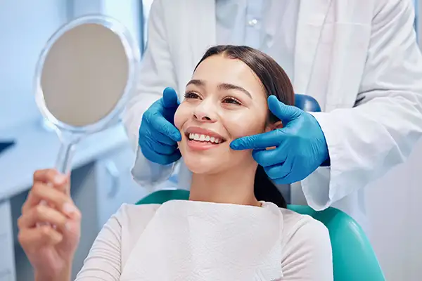 Smiling dental patient looking into mirror after a cleaning at Hoffman Dental in Hillsboro, OR