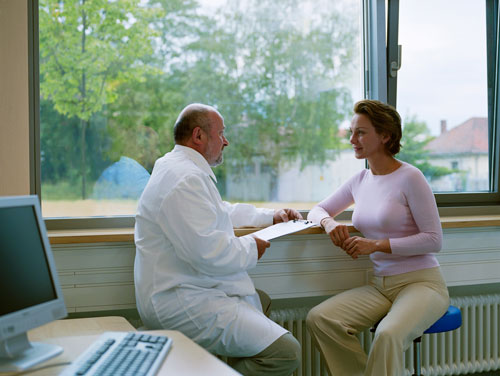 Female patient consulting with male family dentist in front of a window from Cooley Smiles in Everett, WA