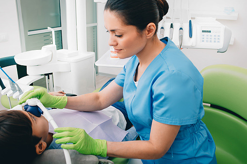 Dental assistant helping a relaxing patient with oral sedation