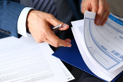 Person wearing a suit reviewing insurance paper forms