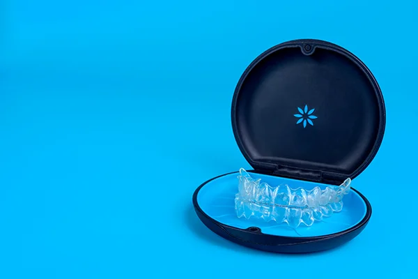 Set of clear aligners resting in an Invisalign® branded case on a blue background at Cooley Smiles in Everett, WA