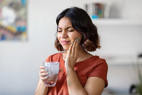 Young woman rubbing her jaw and wincing in pain before emergency treatment at Hoffman Dental in Hillsboro, OR