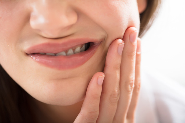 Young woman holds her jaw in pain before she sees Dr. Timothy H. Kindt, family dentist in Mesa AZ for gum disease treatment Young woman holds her jaw in pain before she sees Dr. Timothy H. Kindt, family dentist in Mesa AZ for gum disease treatment