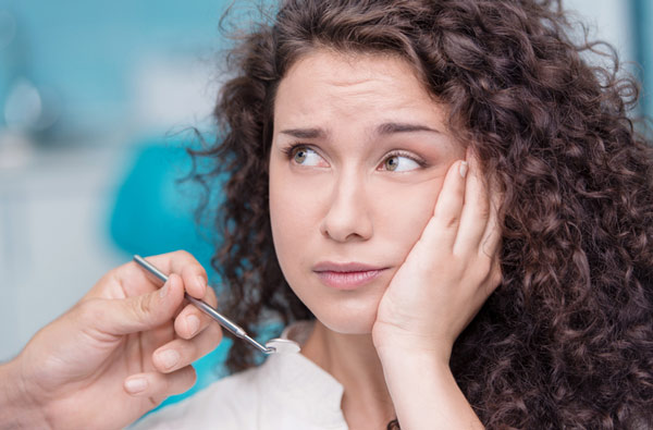 Woman holding cheek before tooth extraction
