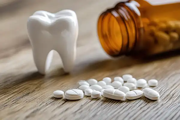 Tooth model sitting beside a small pile of pain relief pills at Hoffman Dental in Hillsboro, OR Tooth model sitting beside a small pile of pain relief pills at Hoffman Dental in Hillsboro, OR