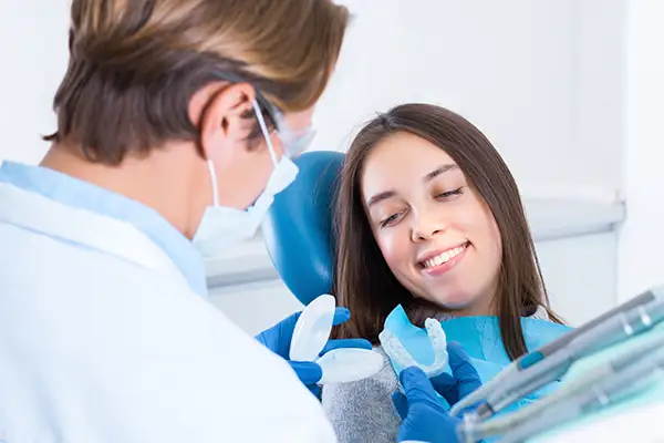 Dentist presenting mouth guard options to a smiling patient at Hoffman Dental in Hillsboro, OR Dentist presenting mouth guard options to a smiling patient at Hoffman Dental in Hillsboro, OR