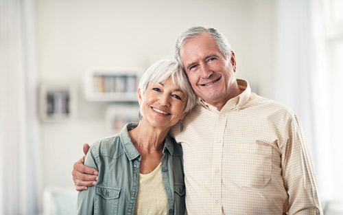 Older couple hugging and smiling with dentures at Jillian Prather Family Dentistry in Owasso, OK