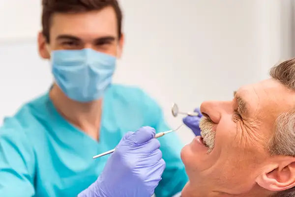 A dentist examining the teeth of a happy and comfortable senior patient at Hoffman Dental in Hillsboro, OR