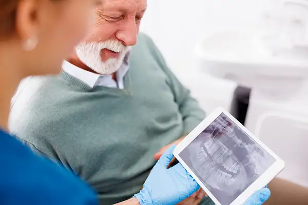 A dental assistant showing a digital x-ray to a senior patient on a tablet at Hoffman Dental in Hillsboro, OR