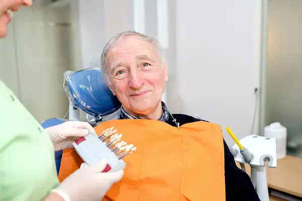 A dentist consults a shade match with a senior patient during a dental care visit at Hoffman Dental in Hillsboro, OR