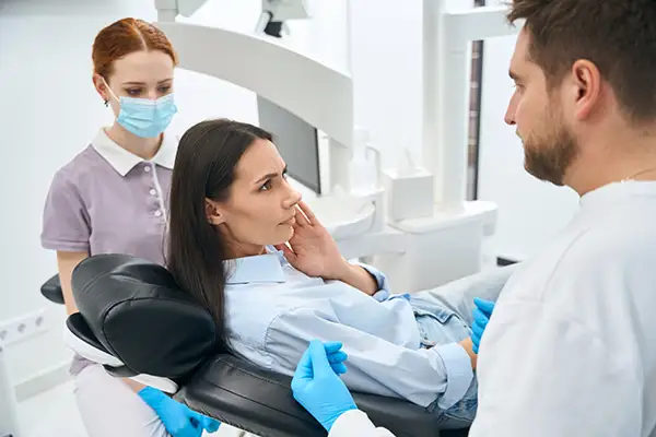 A dentist and assistant examining a female patient with a broken tooth at Hoffman Dental in Hillsboro, OR